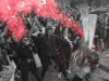 A black and white photo of protesters, mostly female, throwing glitter bombs, which are highlighted in red