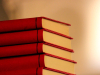 A stack of five red books with a warm glow around it