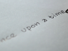 The words "Once upon a time" written on a piece of paper with a ink pen resting but poised to continue on the final stroke