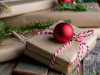 A photograph of books wrapped as gifts with a red ornament laying atop the one in the center