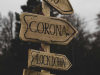 A photograph of a sign. One one arrow, text reads: Corona. On another, text reads: Lockdown.
