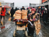 A bread vendor sits next to her piles of bread heaped on a bicycle on a stone plaza in winter