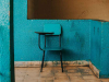 A children's school desk painted blue, sitting in front of a wall painted similarly blue