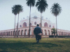 A man in the foreground walks toward Humayun's Tomb, partially shrouded in fog, in New Delhi