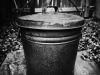 A black and white photograph of a black metal pail
