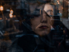 A digitally altered photo of a woman through a window with scenes of the street outside projected on to her face