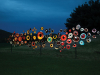 Many round objects, painted like bird's eye are mounted to poles and illuminated at night