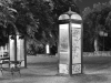 A black and white photo of phone booths, tagged with graffiti and lit up from the inside