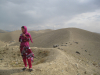 A woman stands on a ridge of sand in a desert landscape