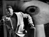 A surreal photograph depicting an African-American man dressed in a suit and carrying a briefcase is running as a giant eye scrutinizes him in the background