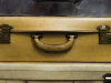A close up photograph of three aged suitcases stacked flat on one another