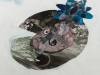 A detail from a larger collage. This detail features a surreal human face nestled within a field resembling a lily pad