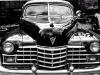 A black and white photograph of an old black Cadillac