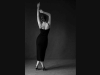 A black and white photograph of a woman dancing, her back turned to the viewer