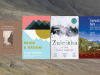 The covers of the four What to Read Now books juxtaposed over a background texture image of a mountainside