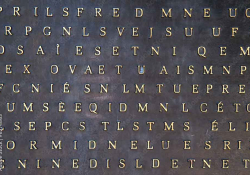 A metal tile with letters printed on it. They do not spell words.