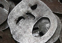 A photograph of a metal fittings with holes cut into them that resemble human faces