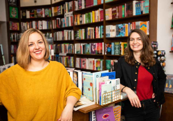 Two women smile at the camera in a bookstore