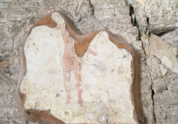 A photograph of a broken piece of mosaic depicting the bottom half of a human figure