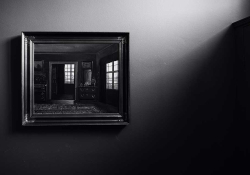A shadowy black and white photograph of a mirror with windows reflected in it. Photo by Wilhelm Gunkel / Unsplash.