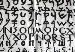 A photograph of the alphabet, each line in a different script, painted on a loose, white cloth