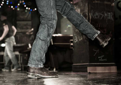 The legs of a dancer, clad in blue jeans and cowboy boots