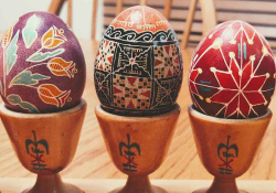 A photograph of three ornately lacquered eggs resting in wooden stands