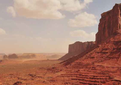 A photograph of a barren Western landscape, with a mesa in the foreground
