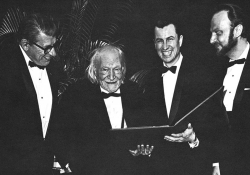 A black and white photo of four men standing in tuxedos