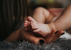 A close up photograph of a mother holding her baby's feet