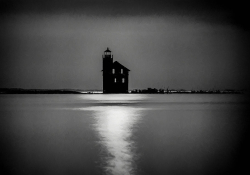 A black and white photograph of a building surrounded by water at night