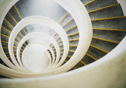A photograph of a downwardly spiraling staircase, shot from above