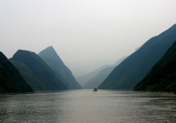A photograph of a foggy river with a boat visible in the distance