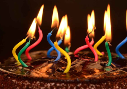 A photo of a chocolate birthday cake, its candles lit but strangely warped