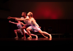 Three dancers lunging to the left, with a dark red background