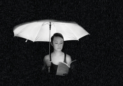 A woman reads a book underneath a lit umbrella