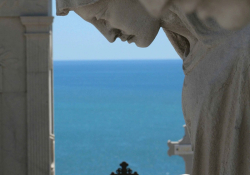 A statuary in the extreme foreground with the sea in the deep background.