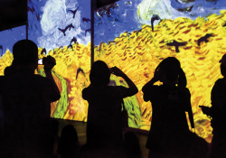 Figures in shadow look at paintings by Vincent van Gogh projected on video screens