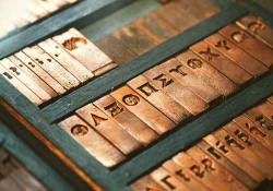 A photograph of Greek letters inscribed in typographical brass fonts