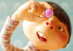 An illustration of a child holding up a candy to look at it. This is detail from the cover to Magic Candies as discussed below
