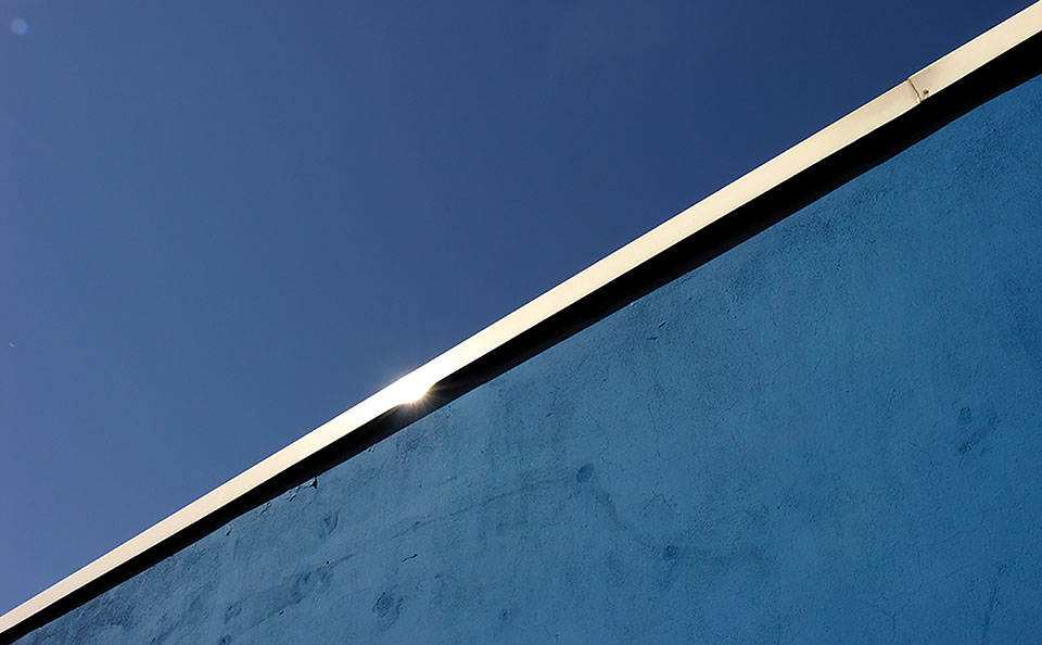 A photograph of the top of a border wall and the blue sky above