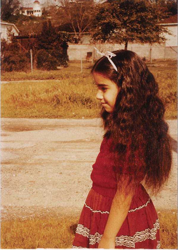 A faded color photograph of a young Margarita in a red dress