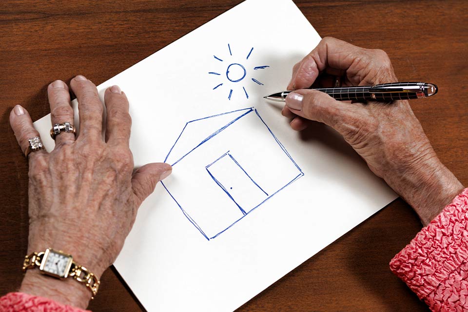 A photograph of Day O'Connor's hands as she draws a house