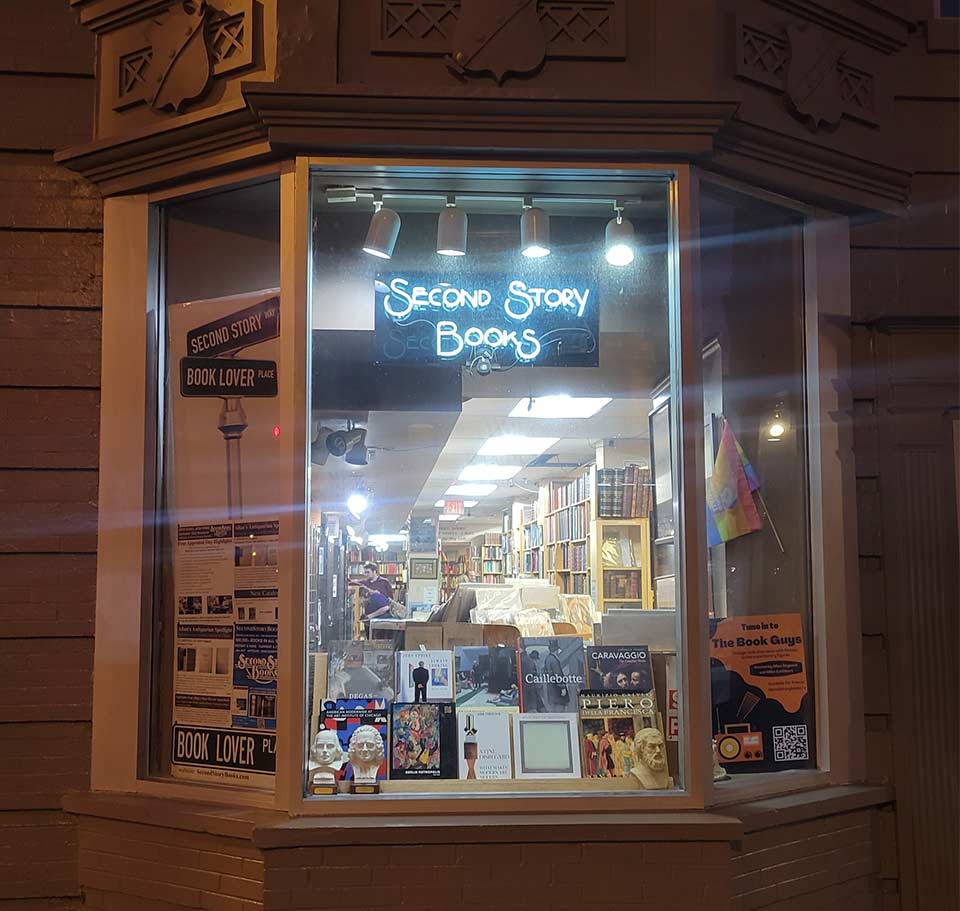 A photograph looking in the window of a bookstore at dusk