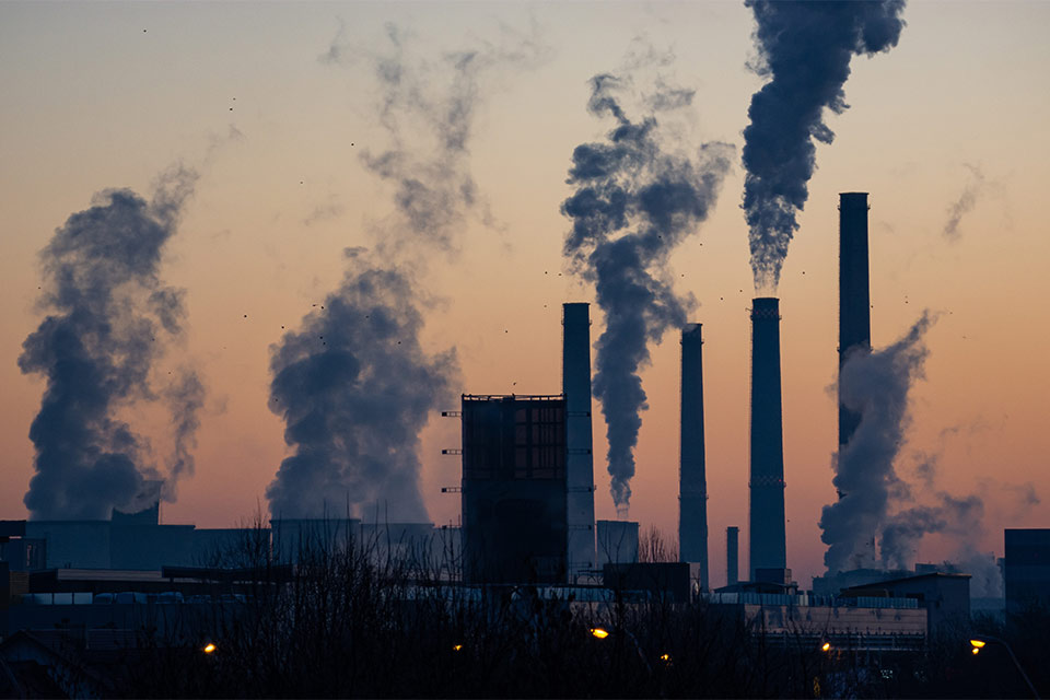 A photograph of an industrial park at dusk, smoke belching from tall stacks