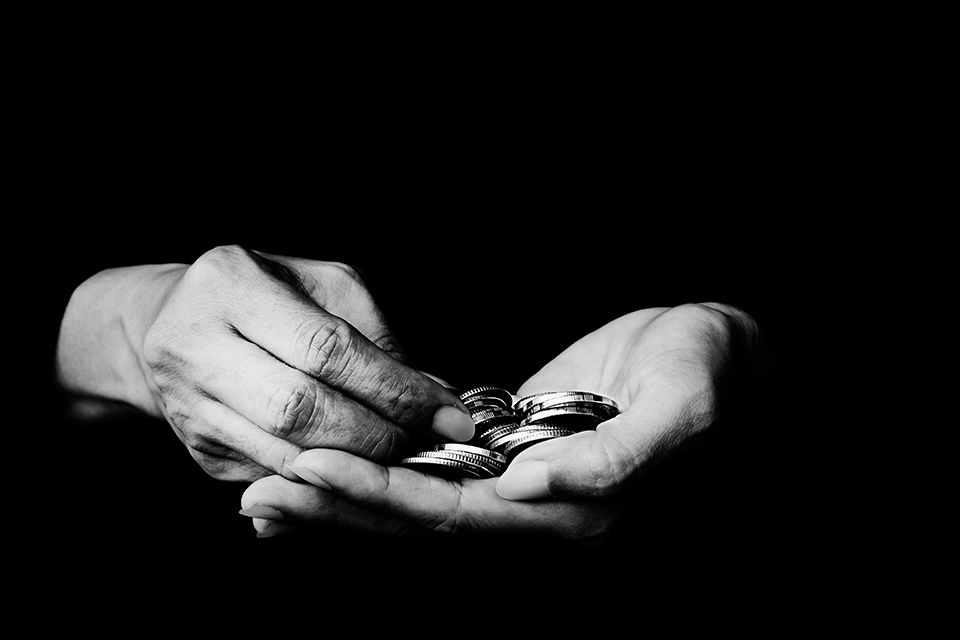 A black and white photograph of a hand holding coins