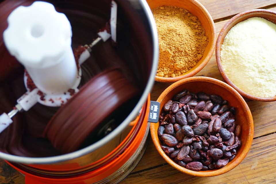 A photograph of a coffee grinder with beans and tumeric on the table