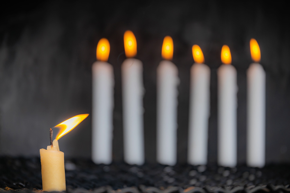 A photograph of six white candles burning
