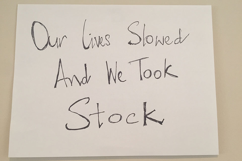 A hand-written sign. Text reads: Our lives slowed and we took stock.