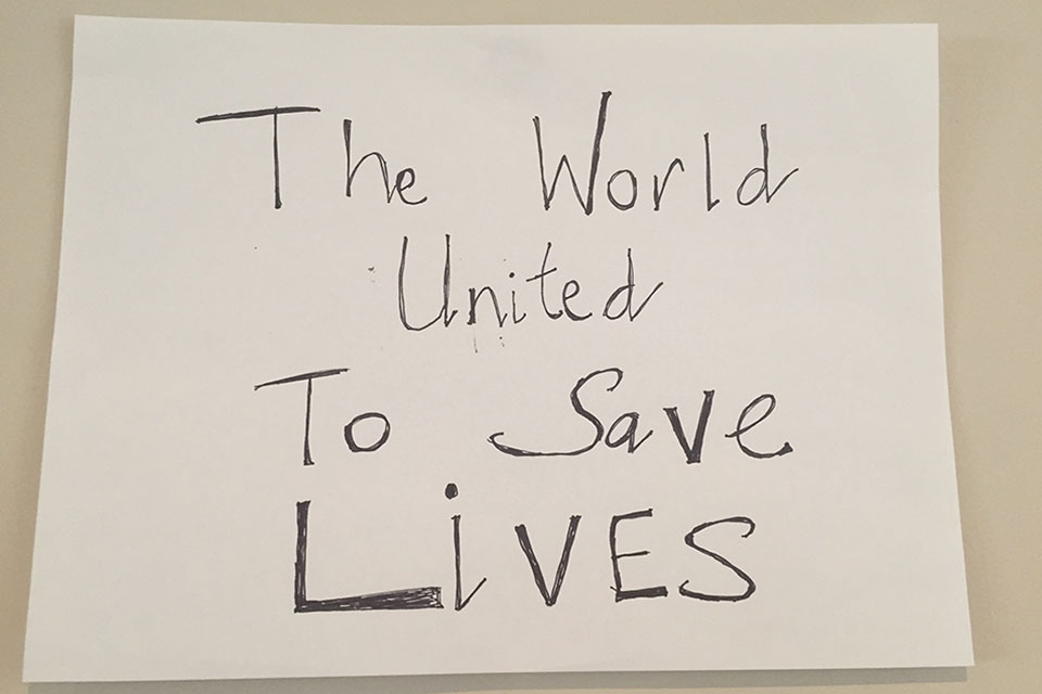 A hand-written sign. Text reads: The world united to save lives.